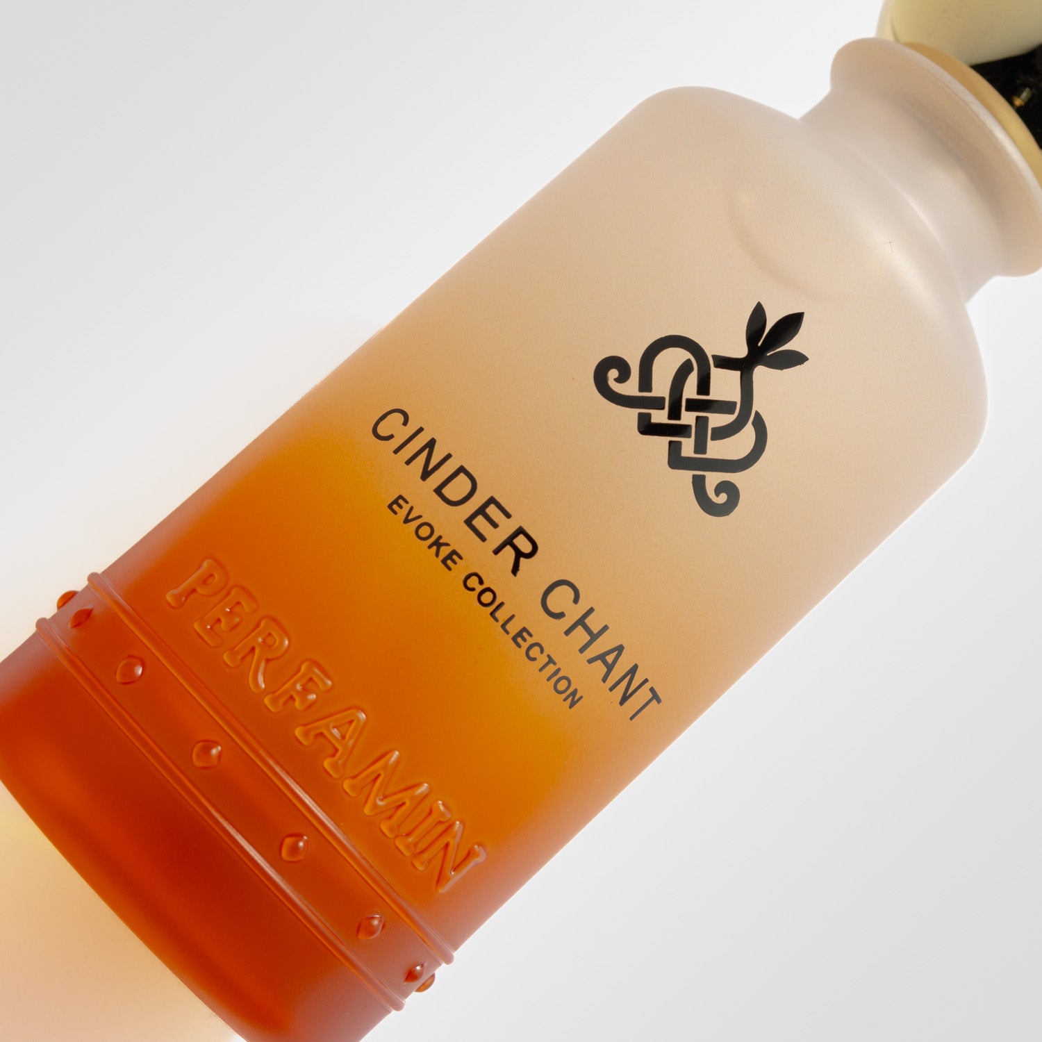 Close up of the gradient glass bottle and Evoke Collection branding for Cinder Chant perfume.