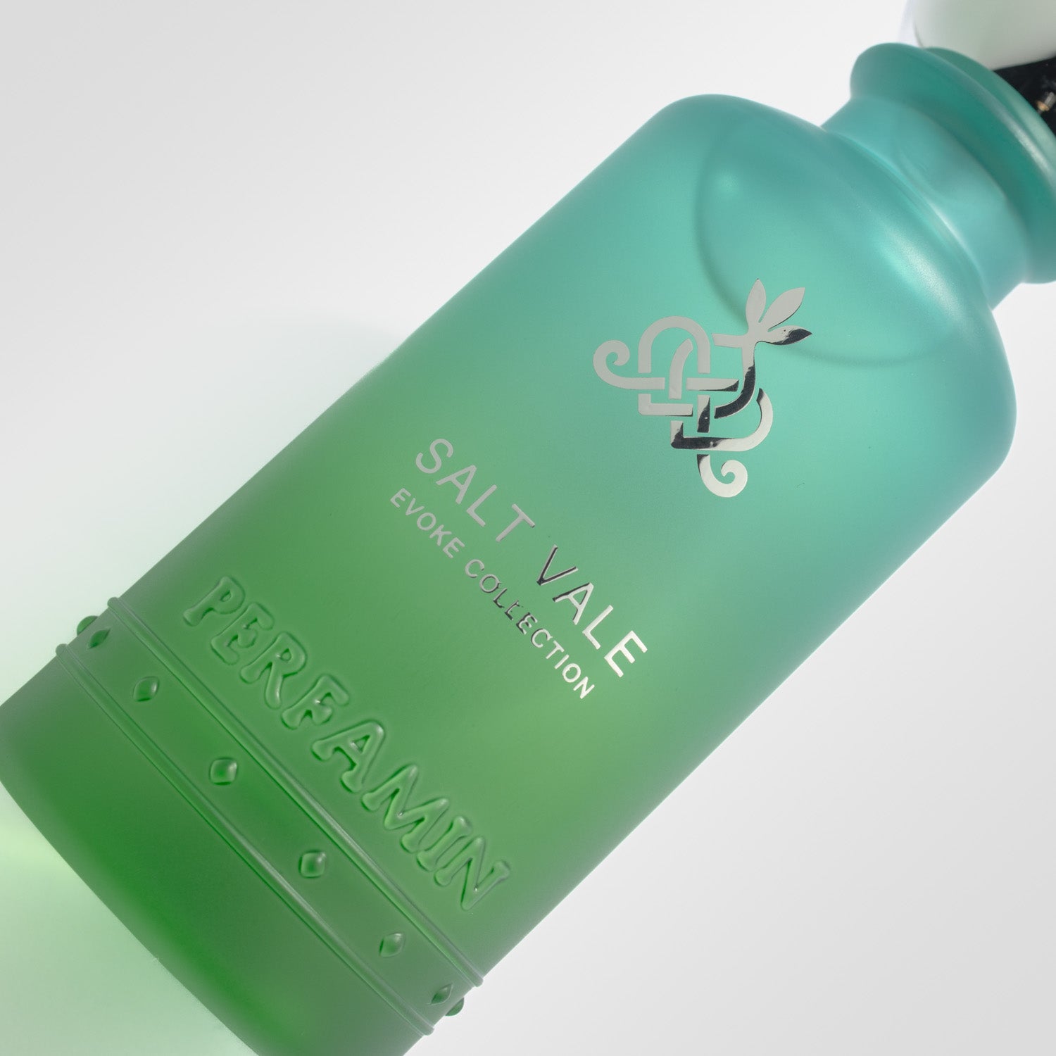 Close-up of Salt Vale Perfamin perfume bottle showing the green gradient glass and Evoke Collection branding